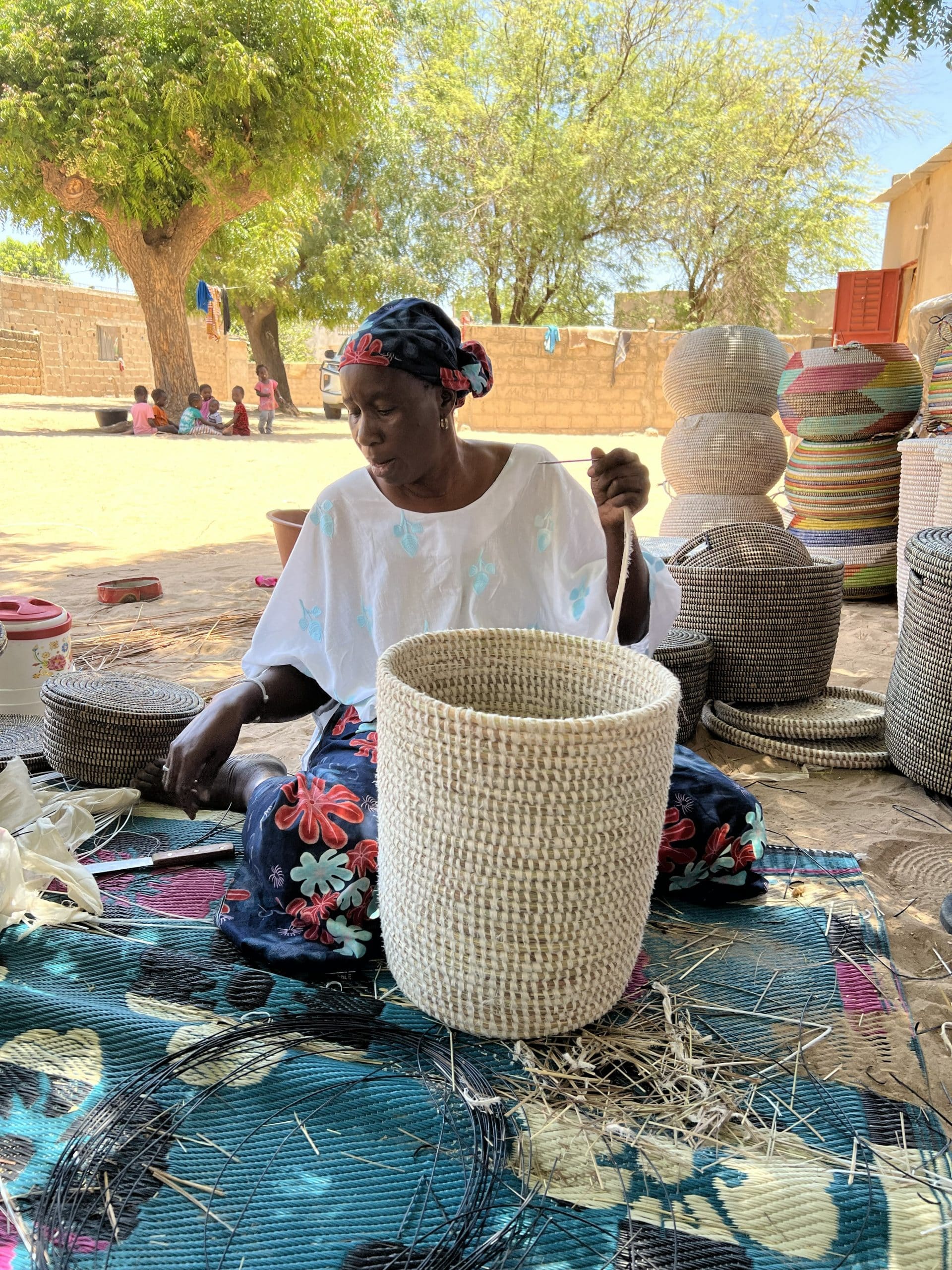 Ambachtsvrouw in Senegal vlecht met de hand een grote Senegalese wasmand